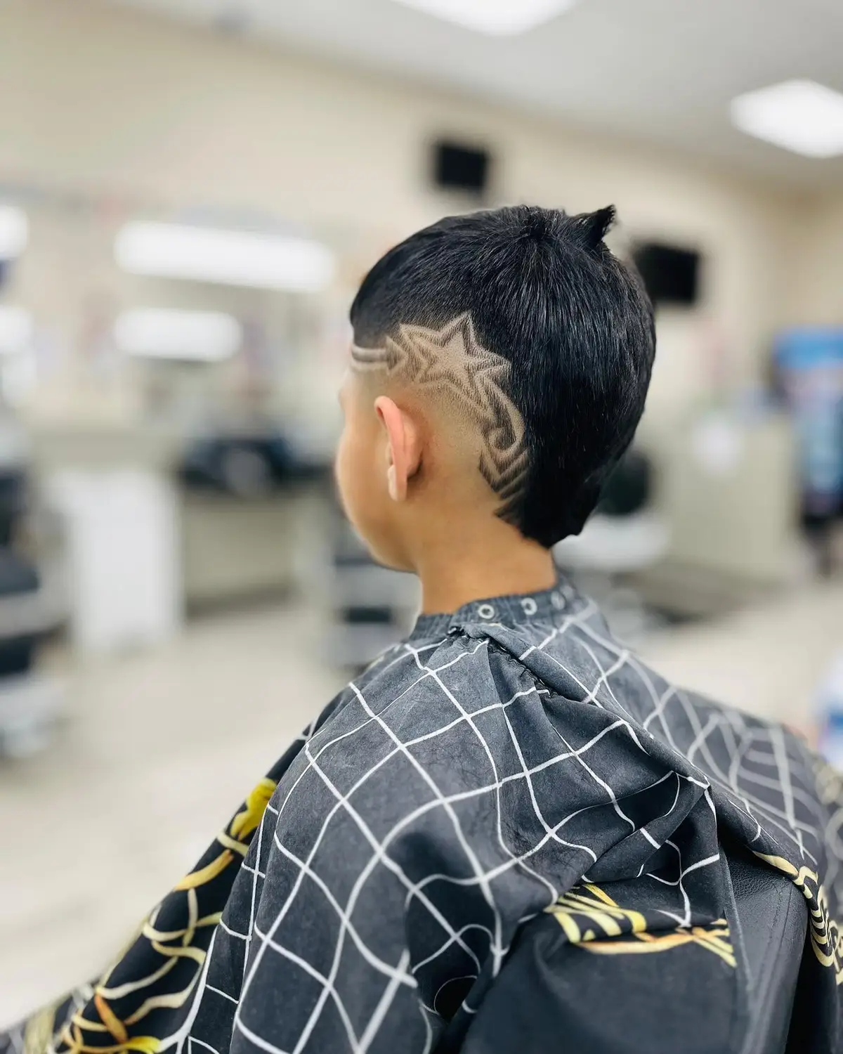 Back view of a kid's haircut with a freehand star design shaved into the side
