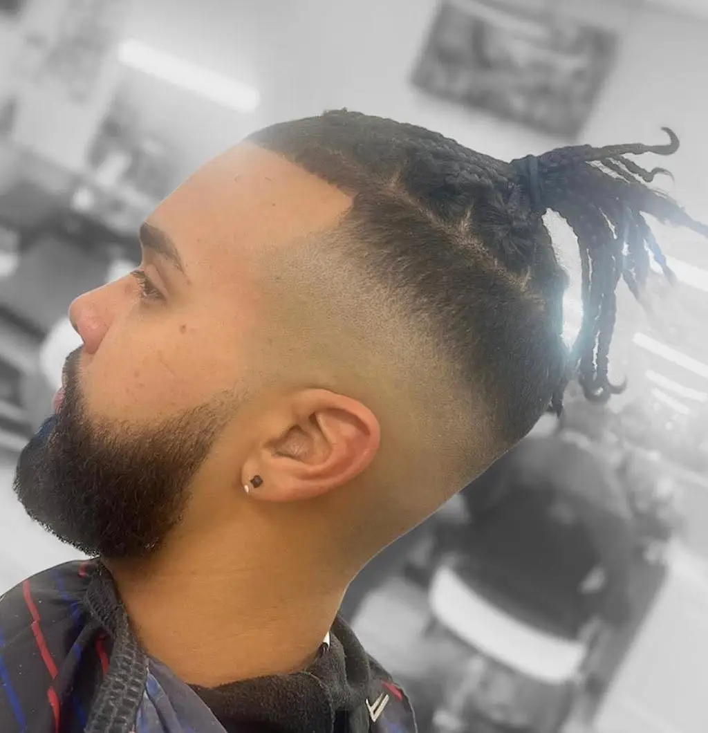 Profile of a high skin fade with braids on top