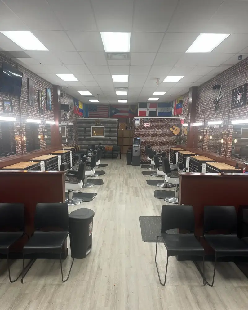 Inside Mago's Barbershop: two rows of barber chairs along brick walls, with flags hanging across the back wall